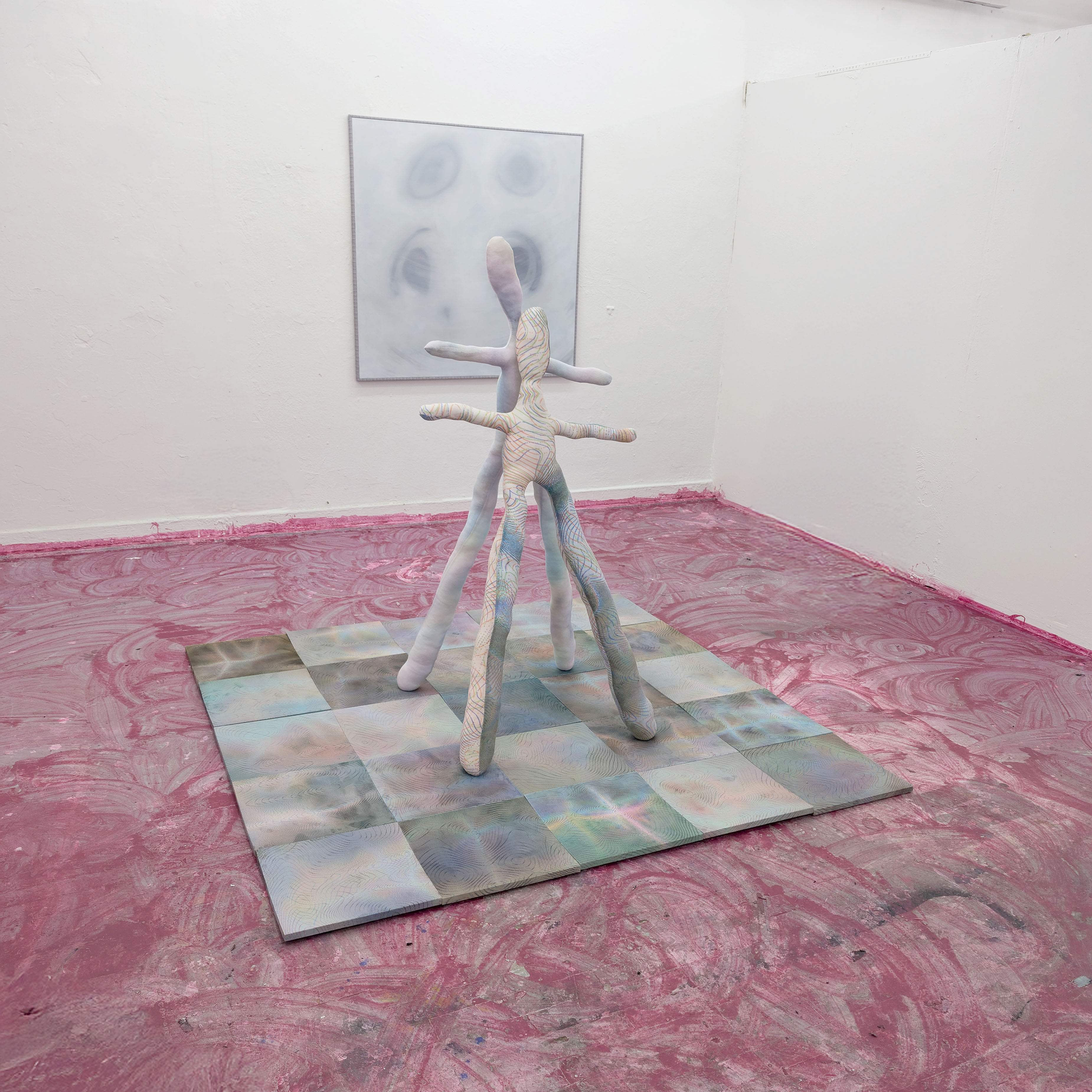 Tejzt – HEGFENCE-RAUM, Installation mit Stoffskulpturen; pinker Boden mit Wischspuren; zentral stehende mehrbeinige Figur; Wandbild in Nebeloptik